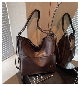Detail view of deep brown faux leather tote bag with subtle texture and front pocket