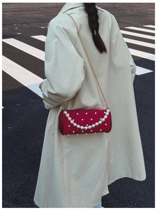 Detail of red cylindrical pearl handbag with satin finish and metal chain strap