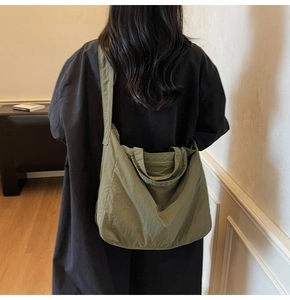 Detail view of large olive green tote bag showing smooth nylon texture and wide strap