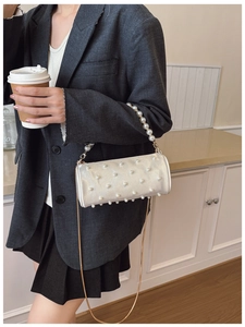 Detail of silver pearl barrel bag with golden metal chain strap and top handle