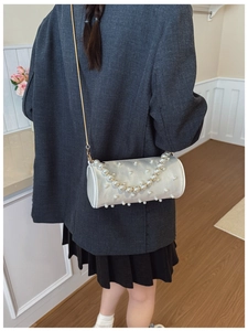 Detailed shot of a pearl cylinder bag with gold chain strap on a stylish grey blazer outfit