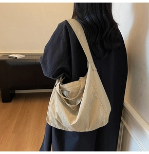 Detail view of a large beige nylon tote bag with crinkled texture and wide shoulder strap