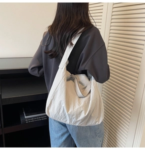 Close-up of large minimalist beige tote bag with wide strap on model back in home setting