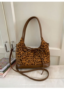 Detail view of leopard print tote bag with brown leather handles and a bow accent