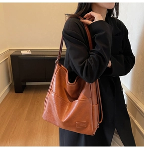 Detail of caramel brown faux leather tote bag with V-shaped stitching and side pocket