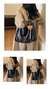 Close-up of black leather tote bag with soft luster and brown teddy bear charm accessory