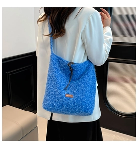 Back view of a model wearing a fluffy blue plush crossbody bag with leather label detail