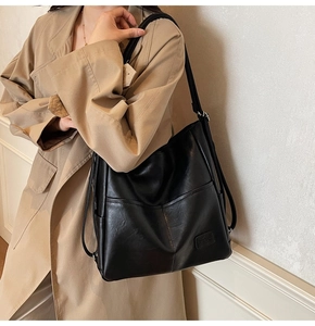 Detail view of large black leather tote bag featuring modern horizontal stitching and texture