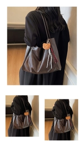 Detail view of deep brown leather tote bag with plush bear charm and woven accents