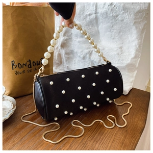 Detail of black cylinder bag featuring large white pearls and a gold snake chain strap