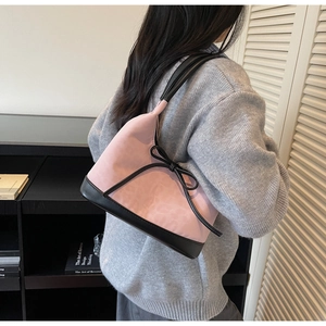 Dettaglio della borsa a secchiello in camoscio rosa con fiocco nero e tracolla chic
