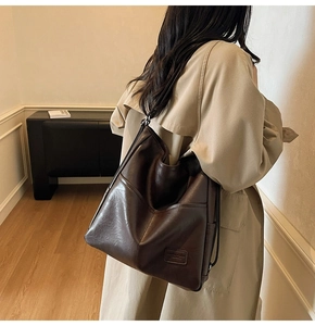Detail view of the large capacity brown leather tote bag with soft texture and logo