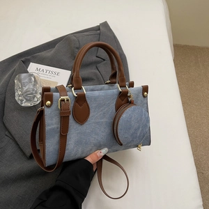 Détail du sac cabas en denim bleu et cuir marron avec une petite pochette ronde