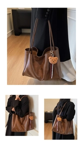 Close-up of dark brown leather tote bag showing texture and plush bear charm detail