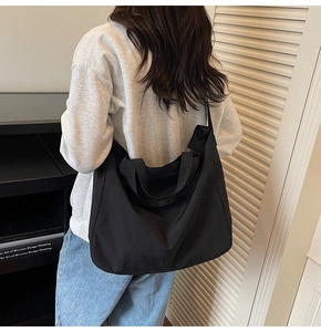 Detail of a large black nylon tote bag worn over the shoulder with a comfortable wide strap