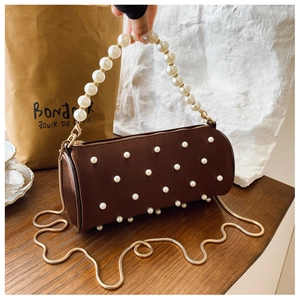 Detailed close-up of brown cylinder pearl handbag with gold chain and satin finish
