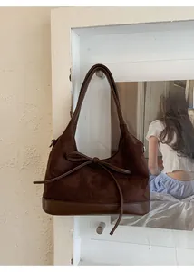 Detail of dark brown suede Hobo bag featuring a sleek leather bow and premium stitching