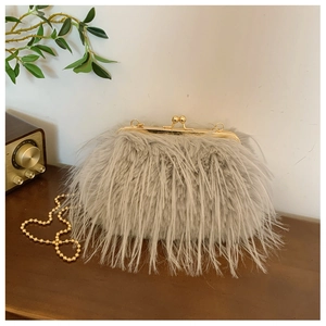 Detail of grey faux fur bag featuring a golden ball clasp and decorative pearl chain