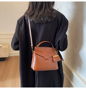 Caramel brown leather handbag featuring a removable mini pouch charm and crossbody strap