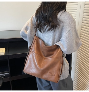 Detail view of the brown leather hobo bag's soft texture and fashion brand label