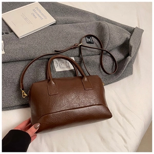 Vue détaillée du sac Boston marron rétro sur manteau en laine avec boucles dorées