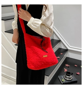 Close-up of red faux fur crossbody bag with drawstring closure and plaid inner lining