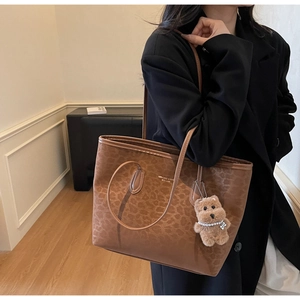 Detail of leopard print tote bag featuring a cute brown teddy bear plush charm and pearls