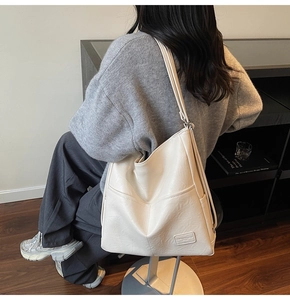 Detail of a large cream tote bag with side pockets and elegant shoulder straps