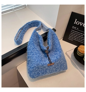 Close-up of fluffy royal blue plush tote bag with brown leather tag and checkered strap detail