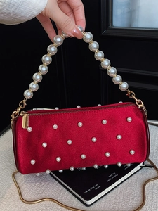 Elegant red velvet pearl handbag with gold chain strap shown in a lifestyle setting