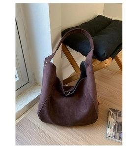 Detail of dark brown matte suede Hobo bag with silver studs on cozy home background