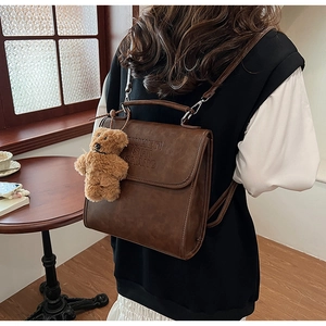 Brown vintage faux leather backpack with flap closure and cute plush bear charm detail