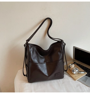 Detail of dark brown leather tote bag with geometric stitching and adjustable strap