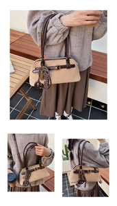 Detail of vintage tote bag with deep brown handles and creative Bonjour pendant charm