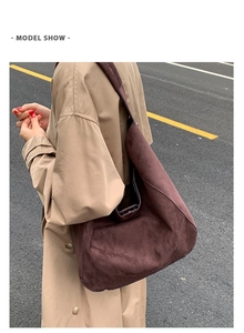 Detail of large dark brown suede hobo tote bag worn by a model in an outdoor setting