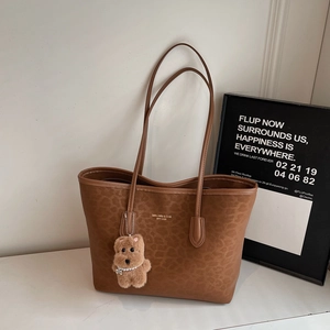 Detailed view of brown leopard print tote bag with plush teddy bear charm and strap