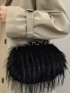 Elegant black turkey feather clutch bag with gold chain strap worn over a beige trench coat