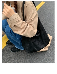 Close-up of black matte suede tote bag styled with a beige trench coat on a street
