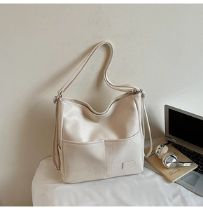 Close-up of cream faux leather tote bag with functional pockets and soft texture detail
