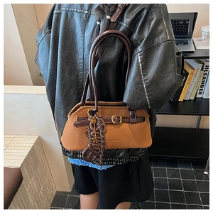Detail showing vintage brown suede tote bag with leather strap and tassel in library setting