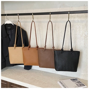 Close-up of woven texture tote bags in four colors hanging on a minimalist display stand