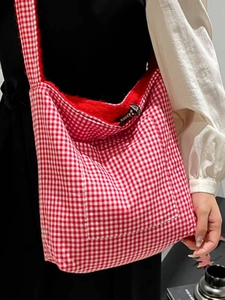 Plaid canvas shoulder bag with red fleece lining and decorative horn buckle closure