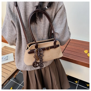 Close-up of vintage tote bag with decorative tassel and brown straps in autumn setting