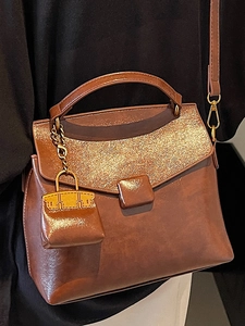 Vintage brown leather handbag for women featuring shimmering glitter panel and shoulder strap