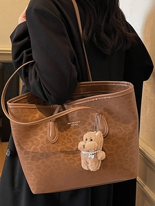 Fashionable brown leopard print tote bag with plush puppy charm shown on a shoulder