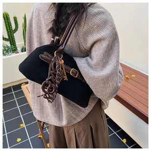 Detail of vintage black shoulder bag with brown leather straps and metal charms on model