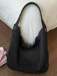 Retro black matte leather large tote bag with silver studs on a wooden floor