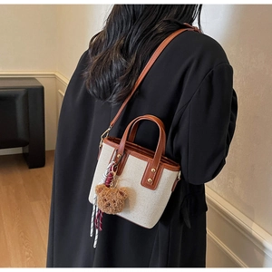 Detail of canvas and leather bucket bag with teddy bear charm and gold rivets