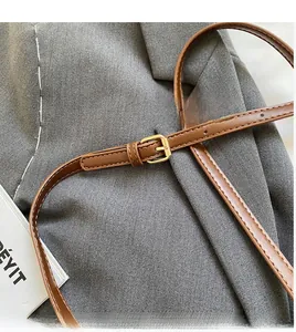 Close-up of brown leather shoulder strap with golden metal buckle and white stitching