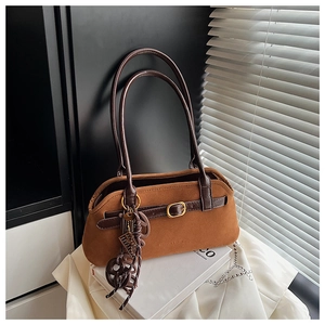 Detail of vintage brown suede tote bag with leather strap buckle and decorative pendant